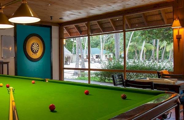 Ein Pooltisch im Meeru Island Resort & Spa mit Blick auf den Garten und den Swimmingpool.