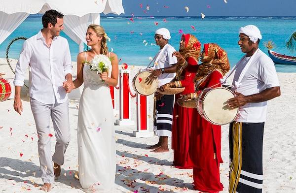 Hochzeitspaar auf dem Meeru Island Resort & Spa Strand mit Musikern und Konfetti