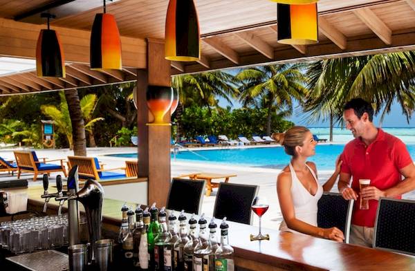 Paar auf der Terrasse des Meeru Island Resort & Spa mit Blick auf den Pool