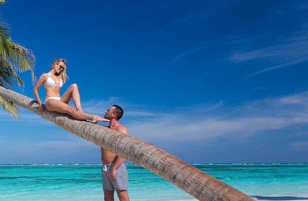 Paar auf einer Palme am Strand des Meeru Island Resort & Spa