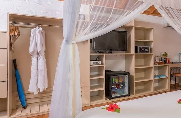 Innenansicht eines Zimmers im Meeru Island Resort & Spa mit einem Bett, Schreibtisch, Fernseher und einem Ausblick auf den Garten.