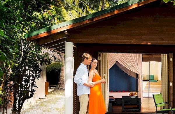 Paar im Meeru Island Resort & Spa vor einer Hütte mit Gartenmöbeln