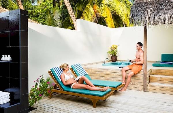 Außenbereich des Meeru Island Resort & Spa mit Lounge-Bereich und Whirlpool.