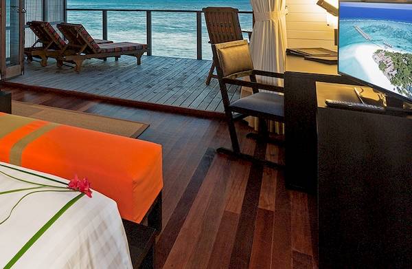 Suite im Meeru Island Resort mit Blick auf das Meer, Möbel und Herz aus Blumen auf dem Bett.
