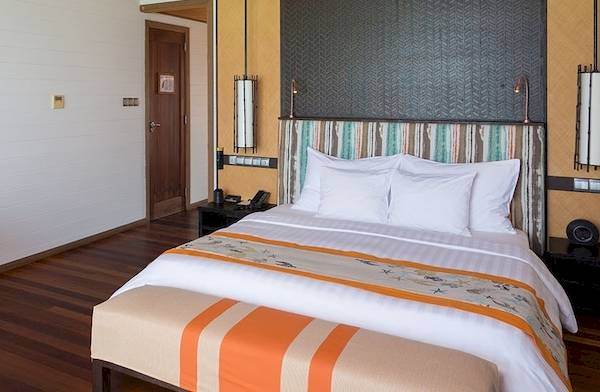 Schlafzimmer im Meeru Island Resort & Spa mit Bett, Couch, Nachttischen und Wandkunst.