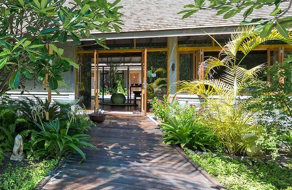 Foto des Eingangs zum Duniye Spa im Meeru Island Resort & Spa, umgeben von grünen Pflanzen und Bäumen.