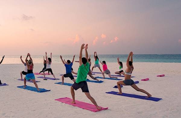 Yoga-Gruppe auf dem Strand des Meeru Island Resorts während des Sonnenaufgangs.