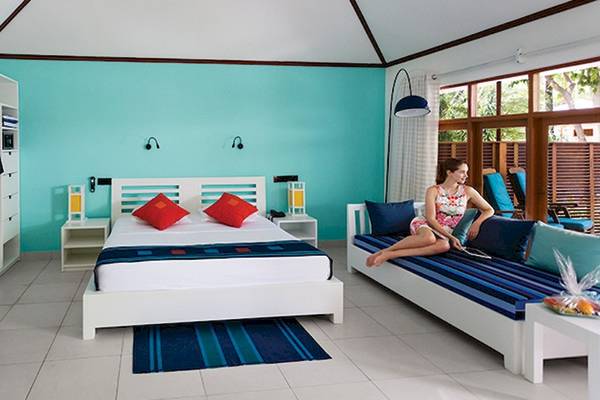 Ein türkisfarbenes Zimmer mit einem Bett, einer Couch und einer Frau, die auf der Couch sitzt.