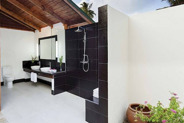 Badezimmer des Meeru Island Resort & Spa mit schwarzen Wänden, weißen Böden und zwei Waschbecken.