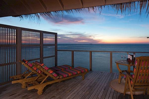 Balkon des Meeru Island Resort & Spa mit Blick auf den Ozean bei Sonnenuntergang.