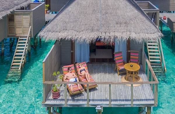 Zwei Personen entspannen in einem ueberwasserbungalow im Meeru Island Resort & Spa.
