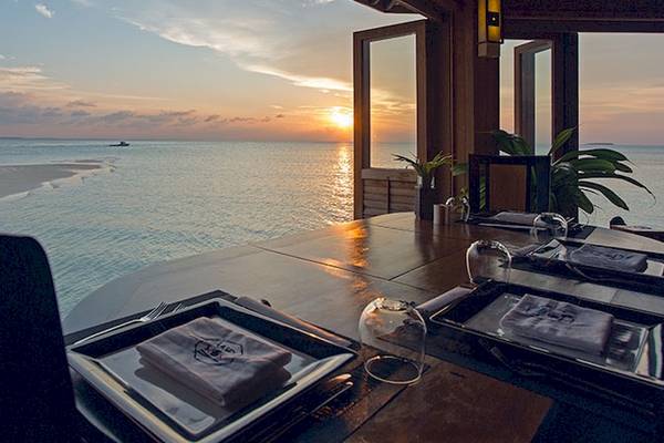 Ausblick auf das Meer vom Meeru Island Resort & Spa mit Sonnenuntergang und gedecktem Tisch.