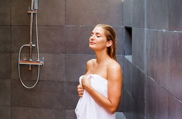 Eine Frau genießt eine Dusche im Badezimmer des Meeru Island Resort & Spa.