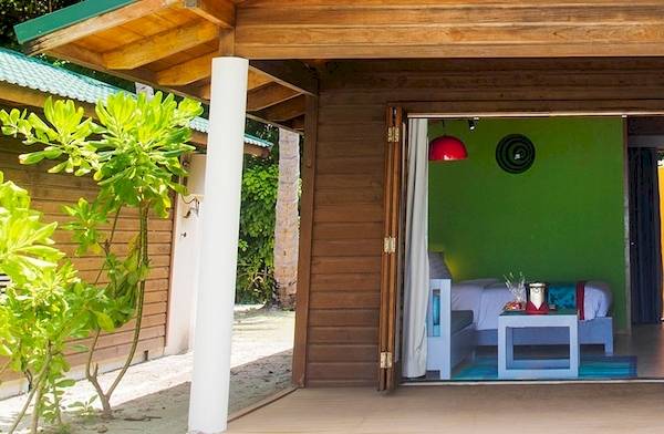 Ein Paar steht auf der Terrasse des Meeru Island Resort & Spa mit einem Glas Wein in der Hand.