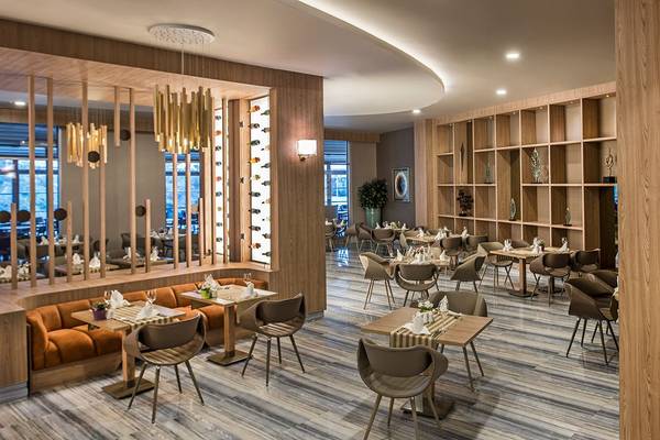 Innenansicht des Restaurants im Delphin BE Grand Resort mit Holzelementen und modernen Möbeln.