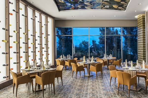 Innenraum des Delphin BE Grand Resort Restaurants mit großen Fenstern und modernen Möbeln.