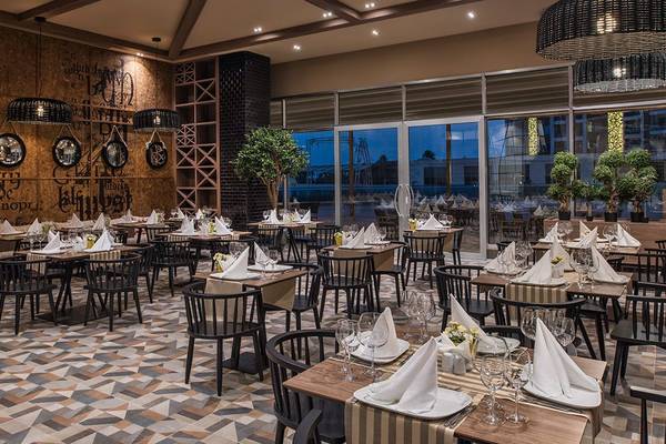 Innenansicht des Restaurants im Delphin BE Grand Resort mit geometrischen Bodenfliesen und gedeckten Tischen.