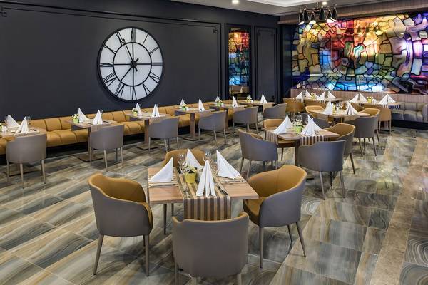 Innenbereich des Delphin BE Grand Resort mit geometrischen Mustern, großen Tischuhren und modernem Interieur.