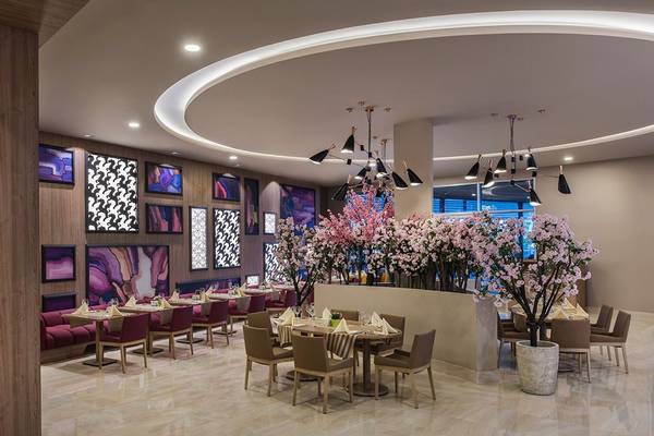 Innenbereich des Delphin BE Grand Resort mit Tisch, Stühlen und Blumendekor.