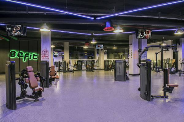Fitnessstudio im Delphin BE Grand Resort mit moderner Ausstattung und neonfarbenen Befit-Schildern.