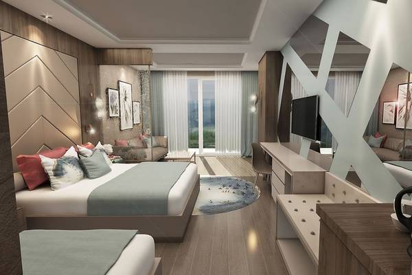 Innenansicht eines Hotelzimmers im Delphin BE Grand Resort mit zwei Betten, Fernseher und geometrischen Wänden.