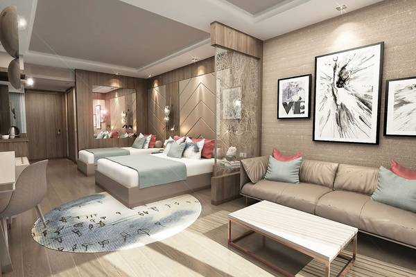 Innenansicht eines Hotelzimmers im Delphin BE Grand Resort mit zwei Betten, einem Sofa und Kunstwerken an der Wand.