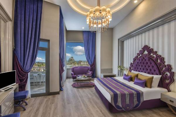Schlafzimmer im Delphin BE Grand Resort mit violetten Vorhängen, einem Bett und einem Schreibtisch