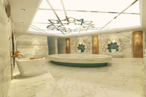 Das Badezimmer des Delphin BE Grand Resort mit Marmorboden und Wänden, goldenen Armaturen und einer zentralen Wanne.
