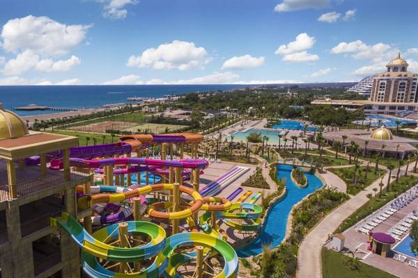 Luftaufnahme des Delphin BE Grand Resort Wasserparks mit bunten Rutschen und Blick auf das Meer
