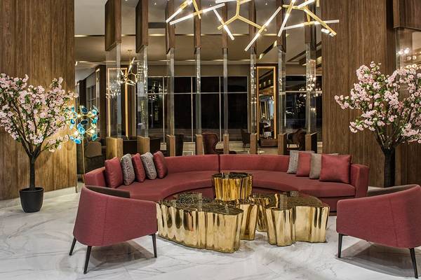 Lobby im Delphin BE Grand Resort mit rotem Sofa, goldenen Tischen und rosa Sträuchern.