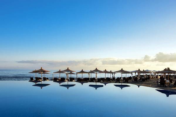Nana Princess Suites Pool am Strand mit Sonnenschirmen und Liegen.