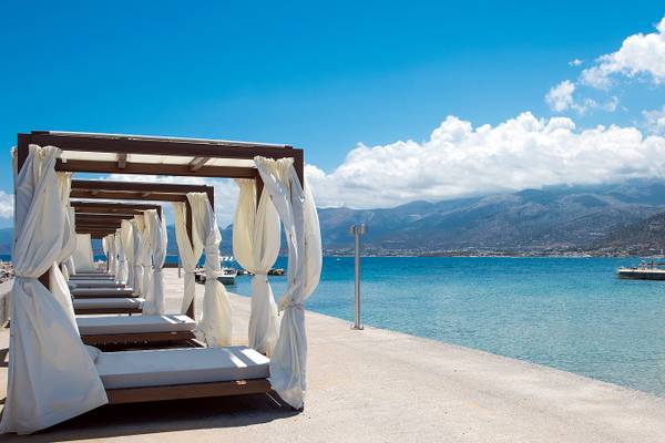Strand mit umhangen Betten am Wasser mit Blick auf das Meer und Berge