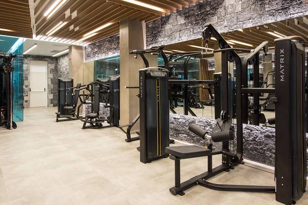 Fitnessstudio im Nana Princess Suites Hotel mit modernen Geräten und einer steinverkleideten Wand.