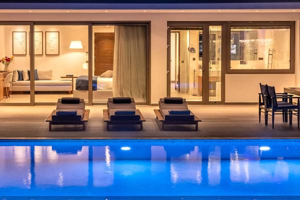 Nachtansicht der Nana Princess Suites mit Pool und Terrasse, die Inneneinrichtung zeigt.