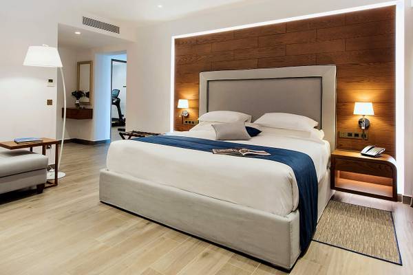 Bett im Hotelzimmer der Nana Princess Suites, Villas & Spa mit blauer Decke und weißem Kopfteil.