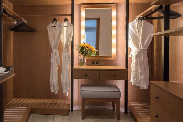 Kleiderschrank in einem Hotelzimmer mit Holzschrank, Spiegel und Nachttisch