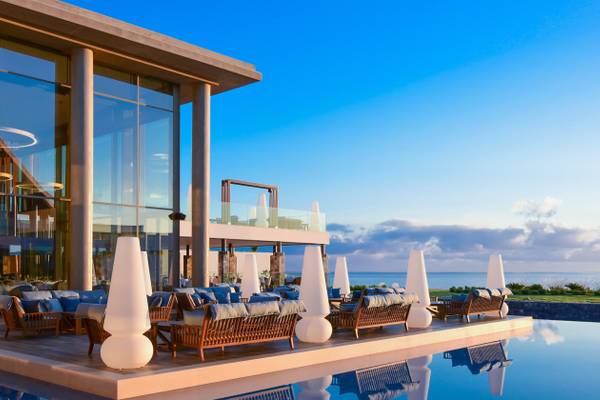 Außenbereich des Nana Princess Suites, Villas & Spa Hotels mit Swimmingpool und Blick auf den Ozean bei Sonnenuntergang.
