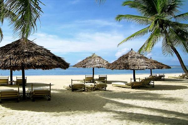 Strand des Diani Reef Beach Resort & Spa mit Sonnenliegen und Strohschirmen