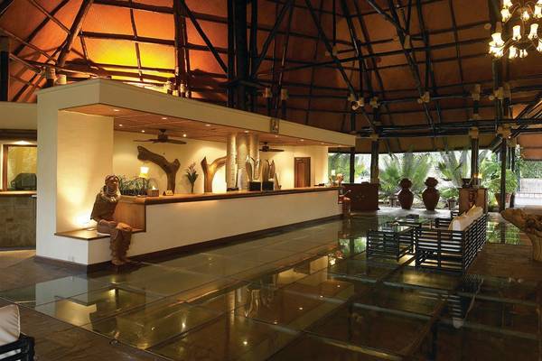 Empfangsbereich des Diani Reef Beach Resort & Spa mit einer Statue und Glasboden.