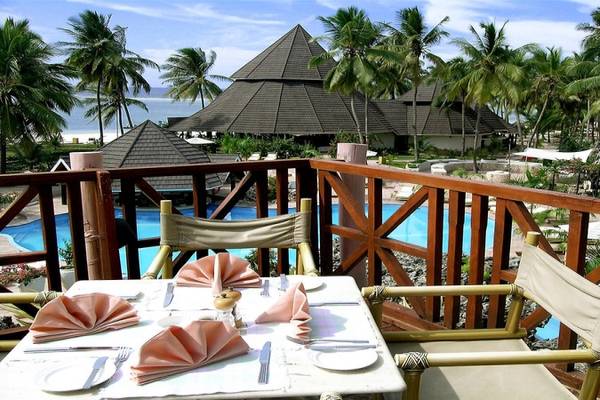 Ein Tisch auf der Terrasse des Diani Reef Beach Resort & Spa mit Blick auf den Pool und das Hotel.