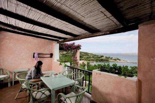 Frau sitzt auf der Terrasse von Bagaglino I Giardini di Porto Cervo und liest ein Buch.