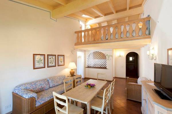 Wohnzimmer mit Sofa, Tisch, Balkon und Fernseher im Bagaglino I Giardini di Porto Cervo Hotel.