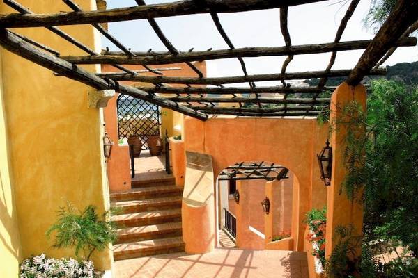 Eingang des Bagaglino I Giardini di Porto Cervo Hotels mit Holzüberdachung und Treppen.