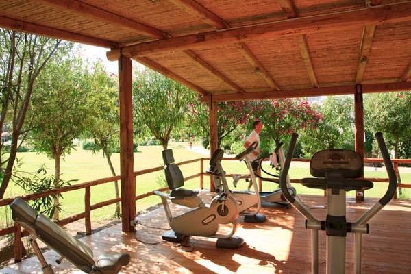 Fitnessbereich im Freien im Hotel Giardini di Porto Cervo mit Geräten und einem Mann, der läuft.