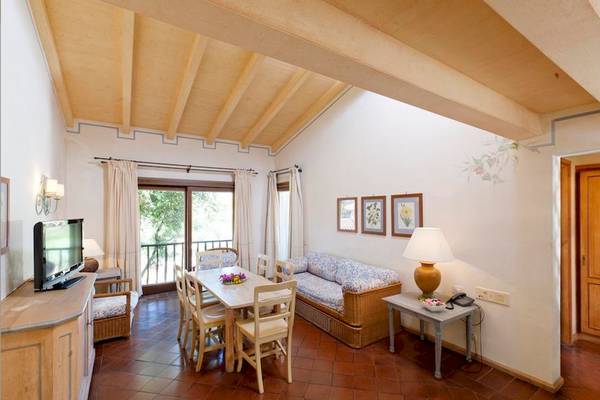 Wohnzimmer im Bagaglino I Giardini di Porto Cervo Hotel mit Tisch, Sofa und Fernseher.