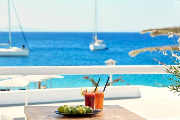 Terrasse des Mykonos Ammos Hotels mit Blick auf das Meer und Cocktails.