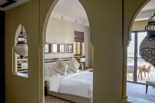 Ein Blick in das Hotelzimmer im Jumeirah Mina A'Salam mit einem großen Bett und Dekor.