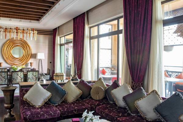 Wohnzimmer des Jumeirah Mina A'Salam Hotels mit einem großen Sofa, vielen Kissen, Esstisch und Stühlen.