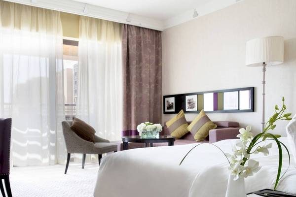 Ein elegantes Hotelzimmer im Jumeirah Mina A'Salam mit einem großen Bett, einem Schreibtisch und einem Wohnzimmerbereich.
