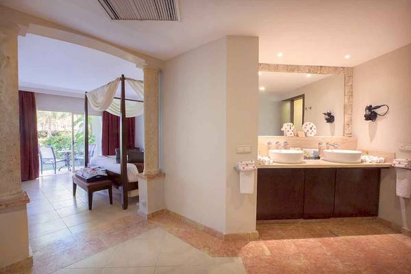 Badezimmer im Majestic Elegance Punta Cana Hotel mit Doppelwaschbecken, Spiegel und Balkonzugang.